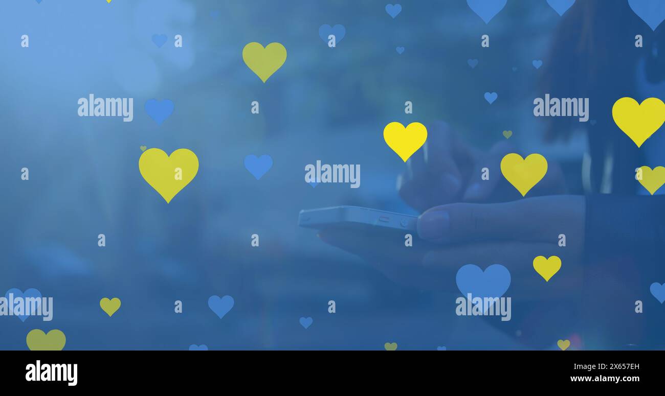 Asian adult holding smartphone surrounded by yellow hearts Stock Photo