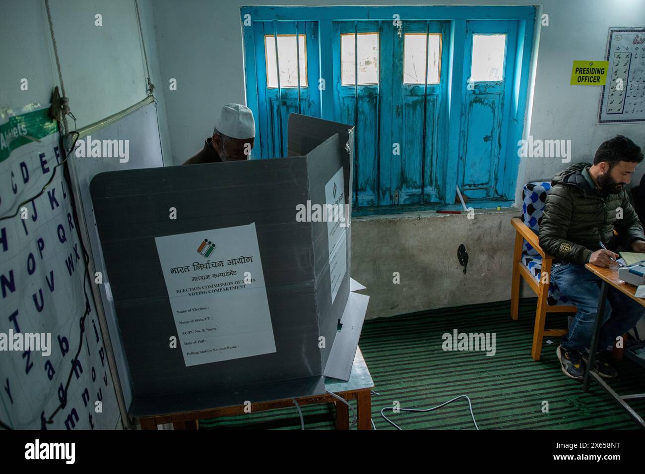 Srinagar, India. 13th May, 2024. A man casting his vote behind a voting booth at a polling station during the fourth phase of the Lok Sabha, or lower house, of the Indian parliamentary elections in a hilly village in Budgam, an area in the Budgam district of Srinagar parliamentary constituency. Credit: SOPA Images Limited/Alamy Live News Stock Photo