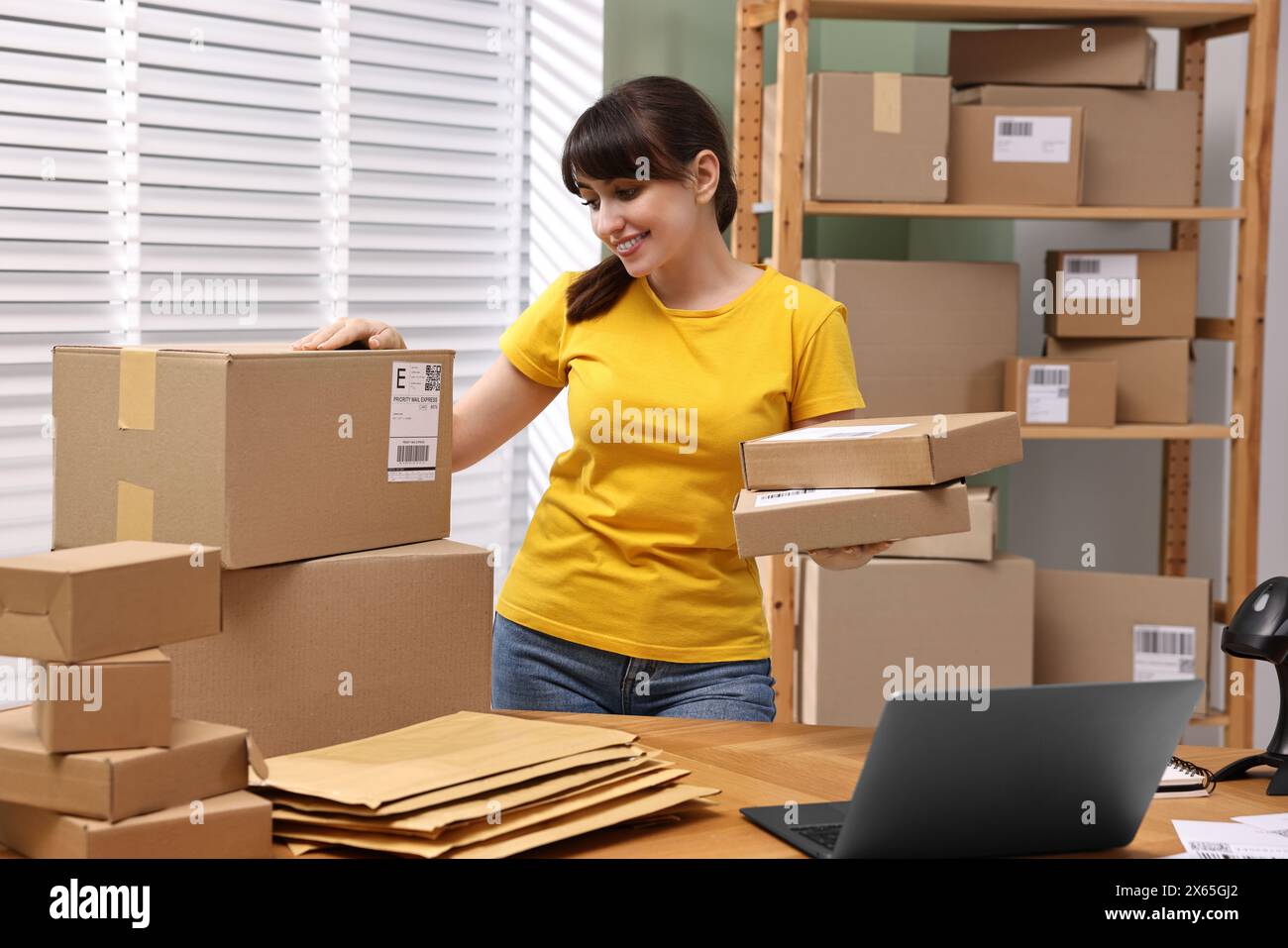 Parcel packing. Post office worker with parcels at wooden table indoors Stock Photo