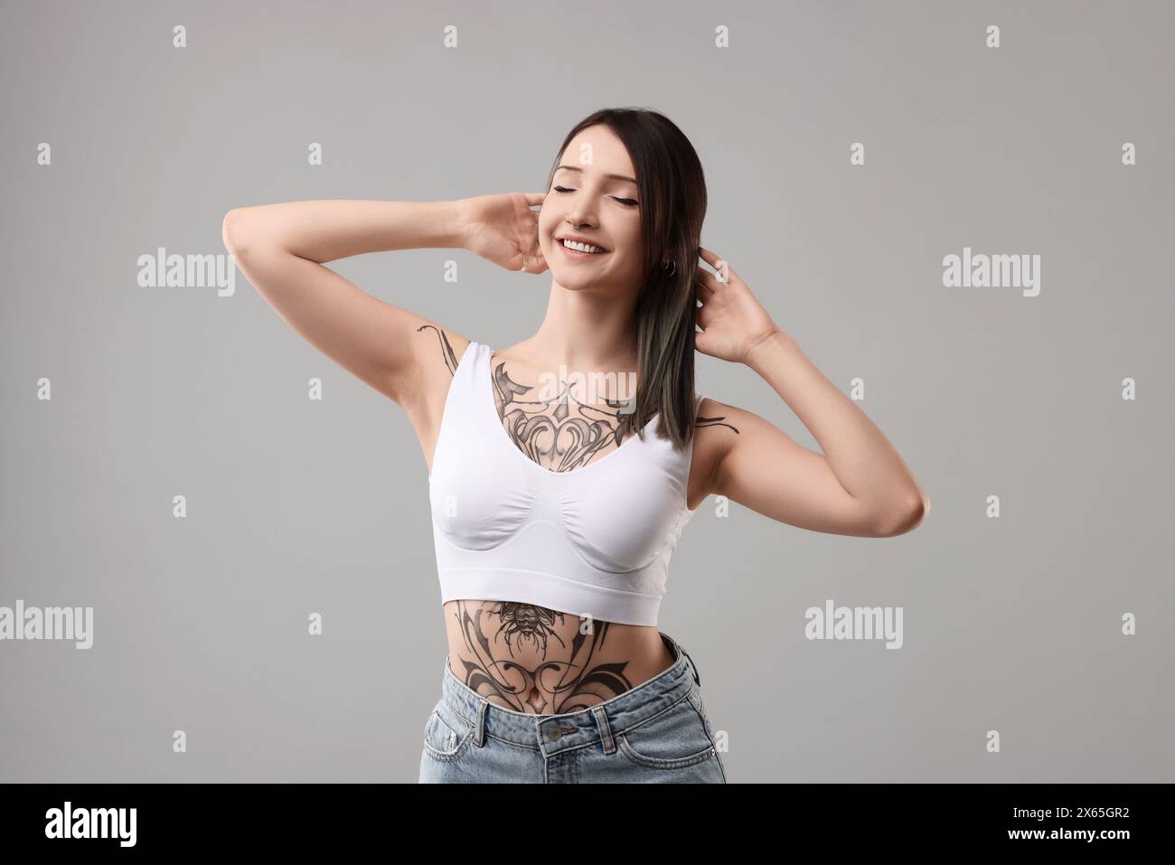 Portrait of smiling tattooed woman on grey background Stock Photo