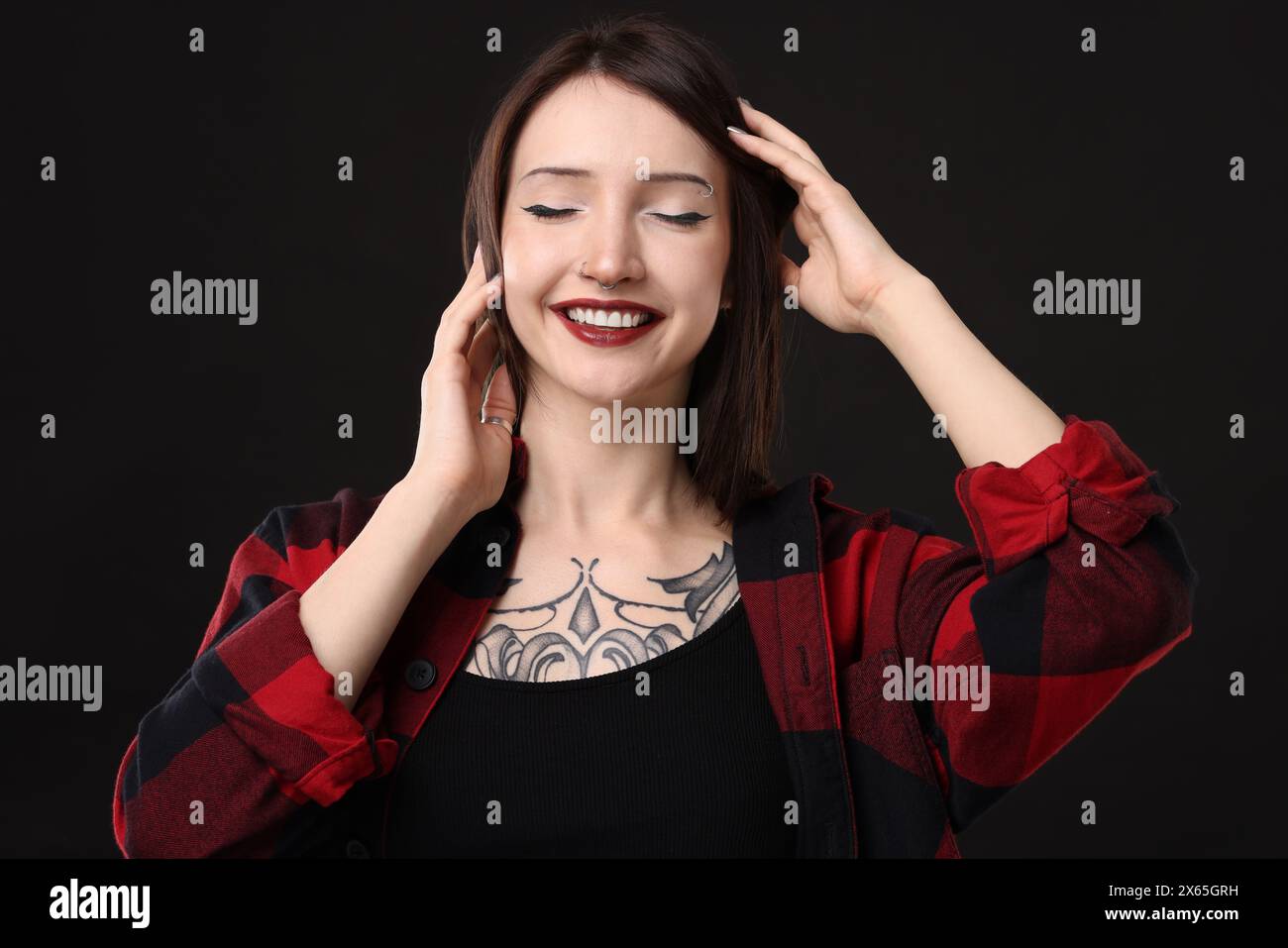 Portrait of smiling tattooed woman on black background Stock Photo