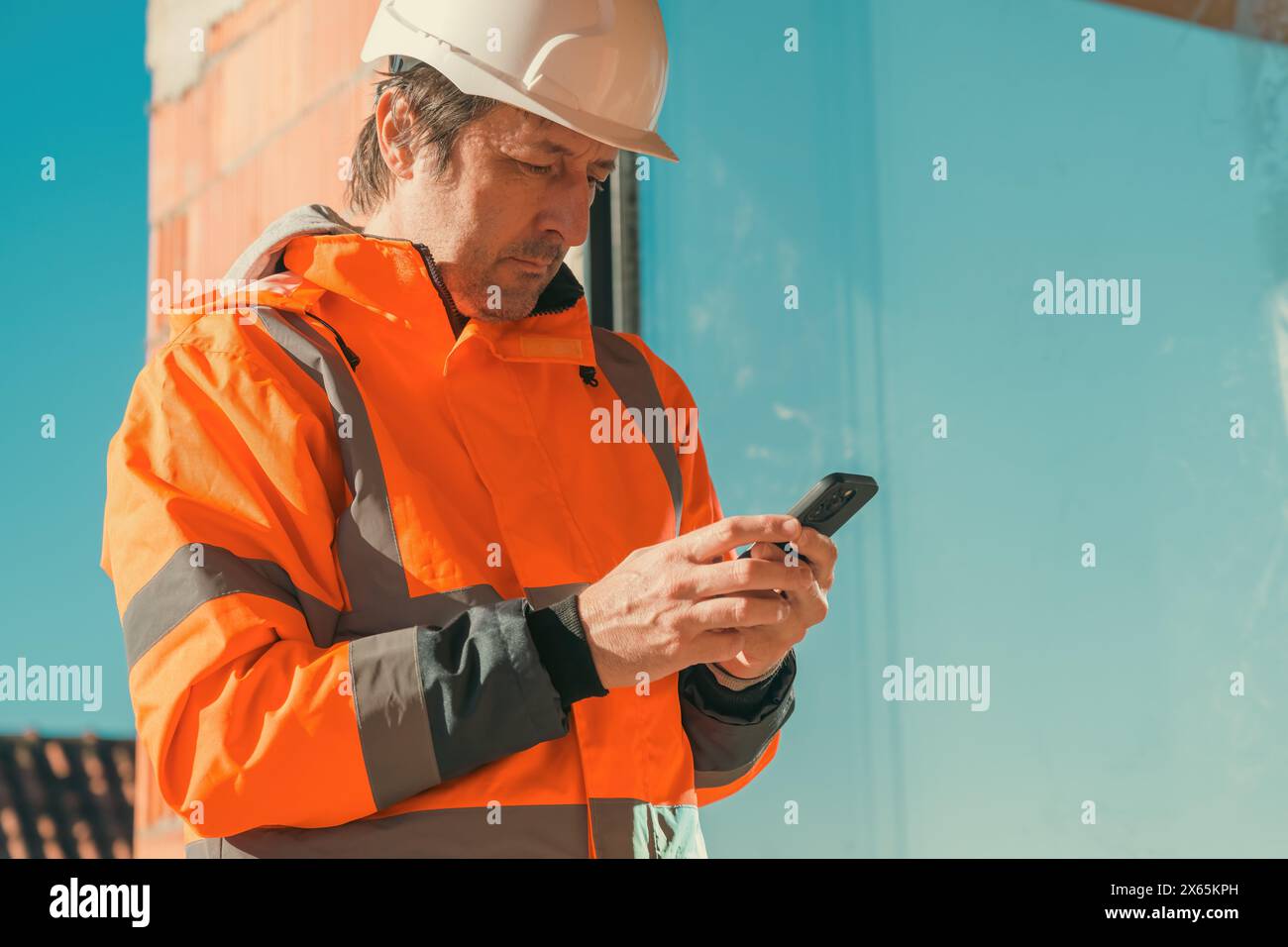 Construction engineer using mobile smart phone on site during inspection, selective focus Stock Photo