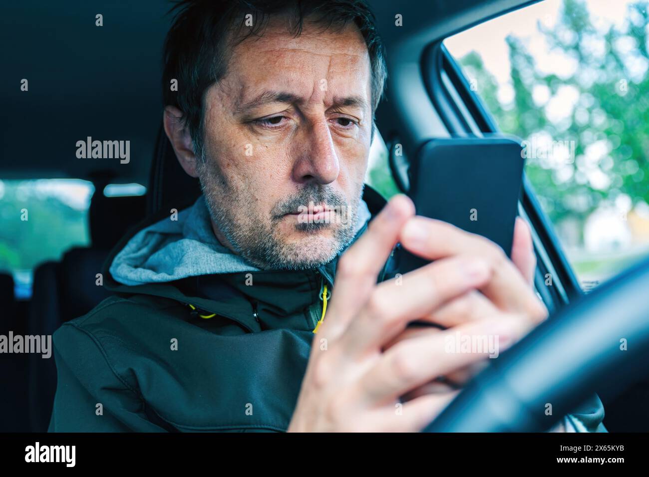 Male driver using smartphone device in car, selective focus Stock Photo