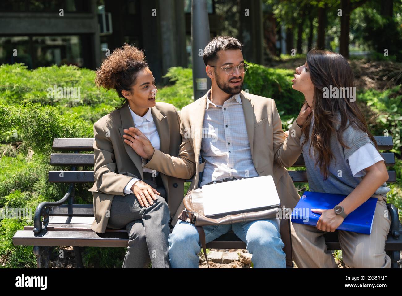 Group of young business people, businessman and two businesswoman, colleagues, sitting out of office building having argue and disagreement about job Stock Photo