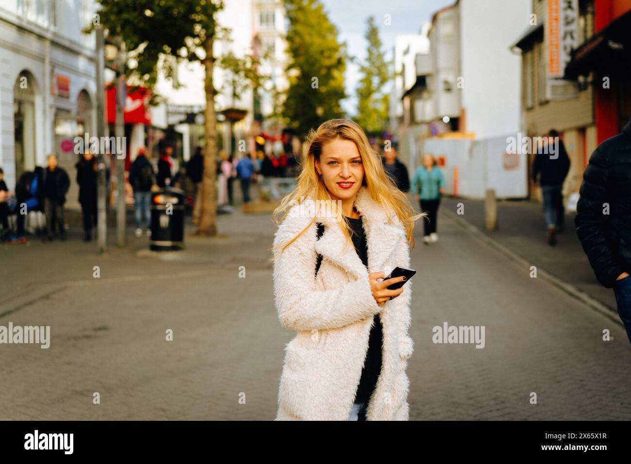 Smiling woman using mobile phone on the street. Stock Photo