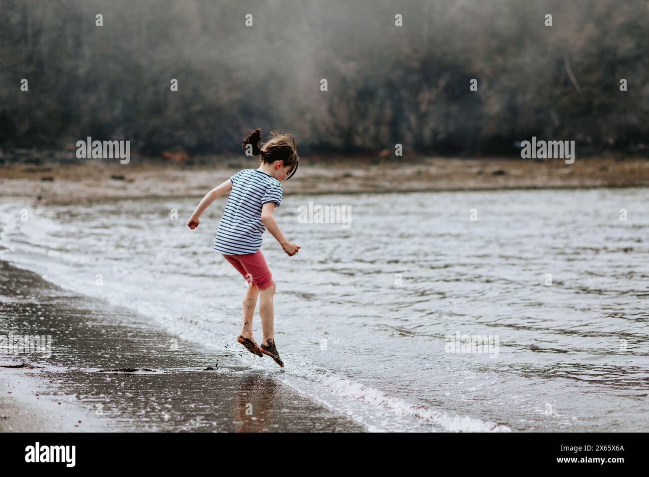 Young girl jumps over waves in Lorneville New Brunswick Stock Photo
