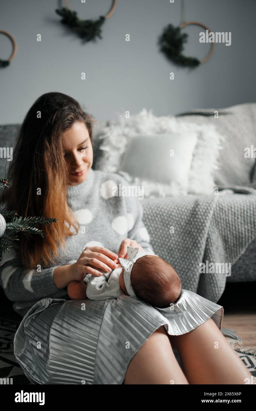 A young smiling mother holds her little daughter in her arms Stock Photo