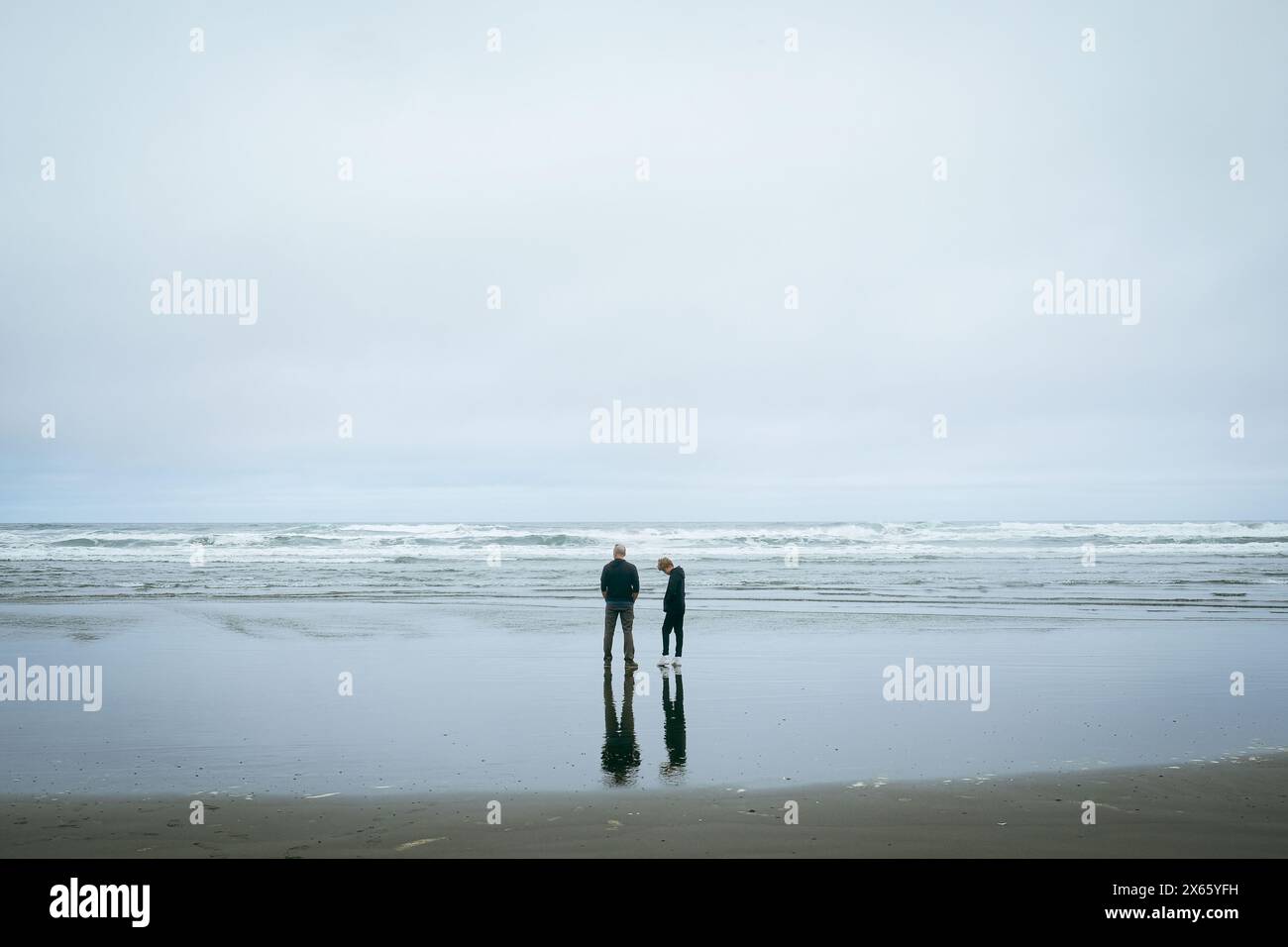 Two people look out in the vast ocean in winter. Stock Photo