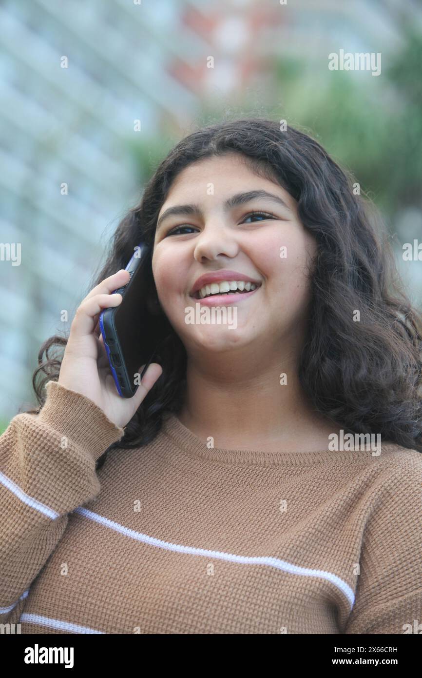 portrait of a young latin girl with a beautiful smile talking on a ...