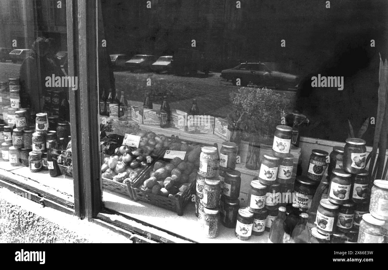 Romania, May 1990.  A few months after the anti-communist revolution of December 1989, food was still scarce. The front window of a grocery store displaying the few items available, mostly canned food and some produce. Stock Photo
