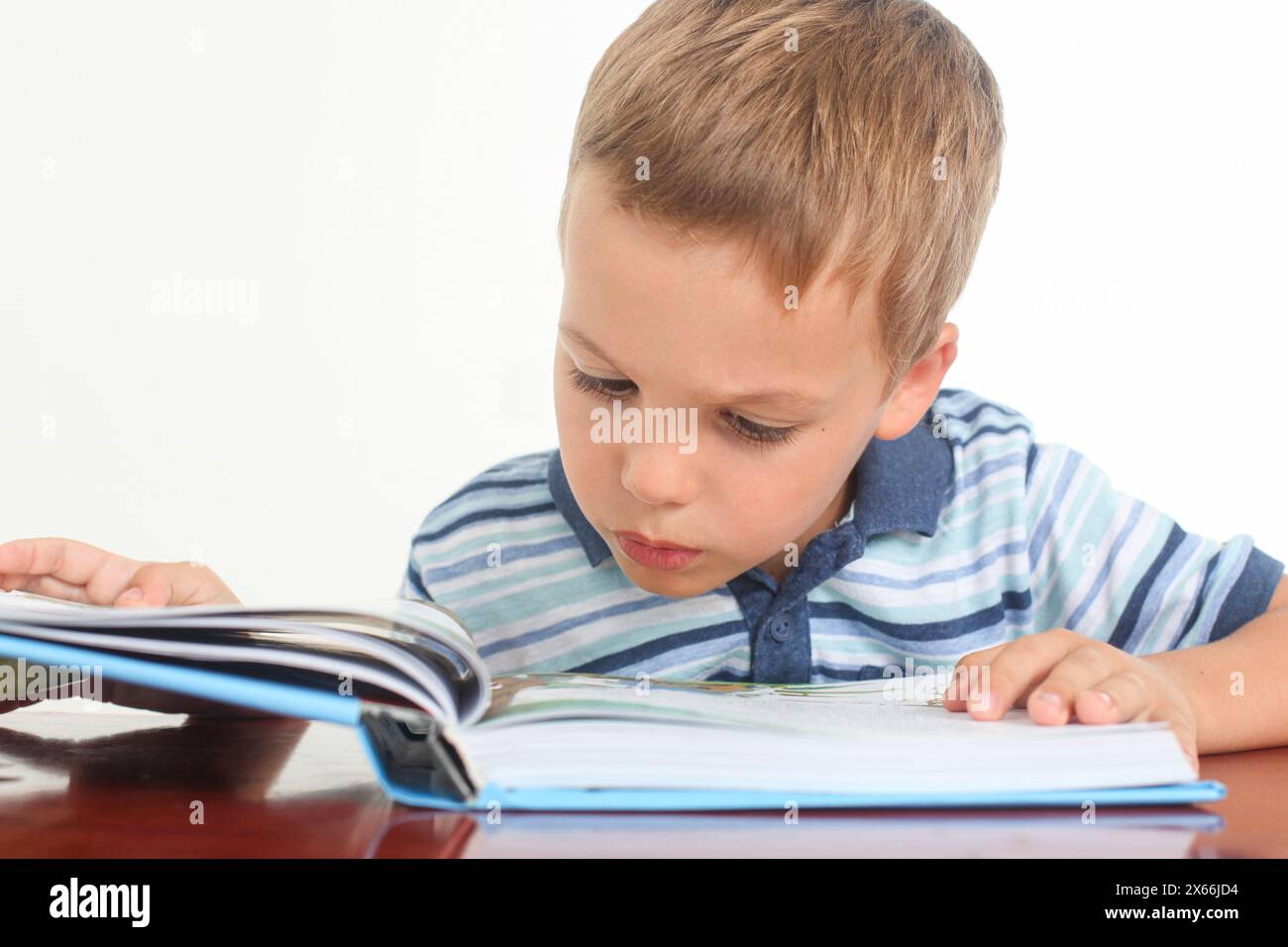 puzzled little boy reading a book in studio Stock Photo