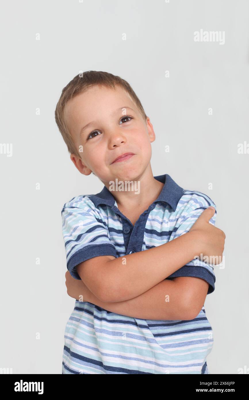 puzzled little boy looking up and thinking on white background Stock Photo