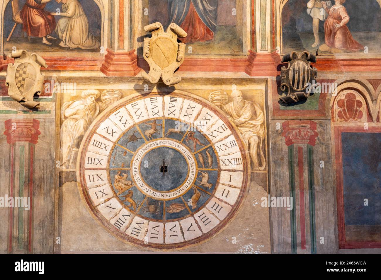 Detail of decorative frescoes and medieval clock painted on church wall in Italy Stock Photo