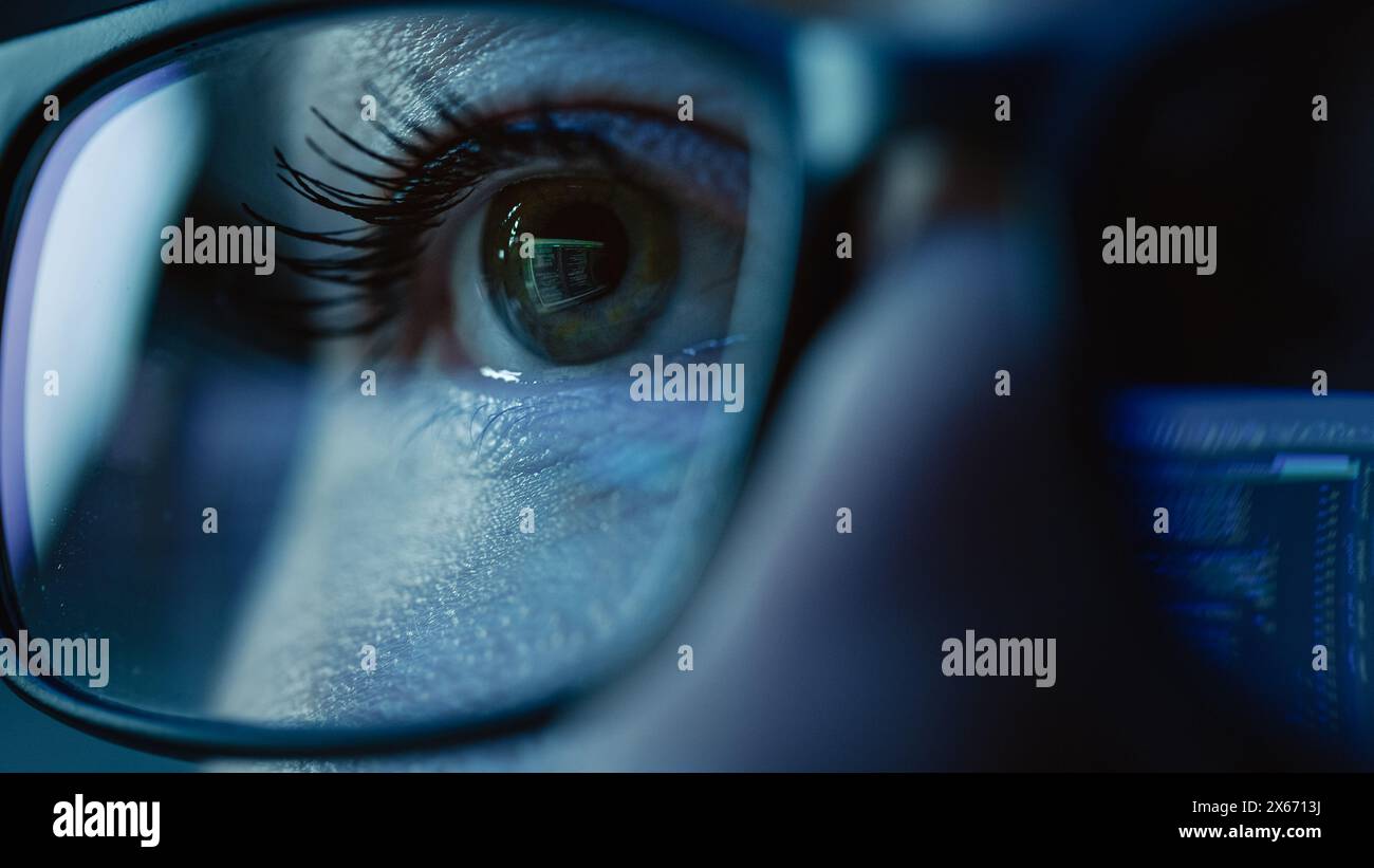 Super Close-up on Female Eye, Software Engineer Working on Computer, Programming Reflecting in Glasses. Developer Working on Innovative e-Commerce Application using Machine Learning, AI, Big Data Stock Photo