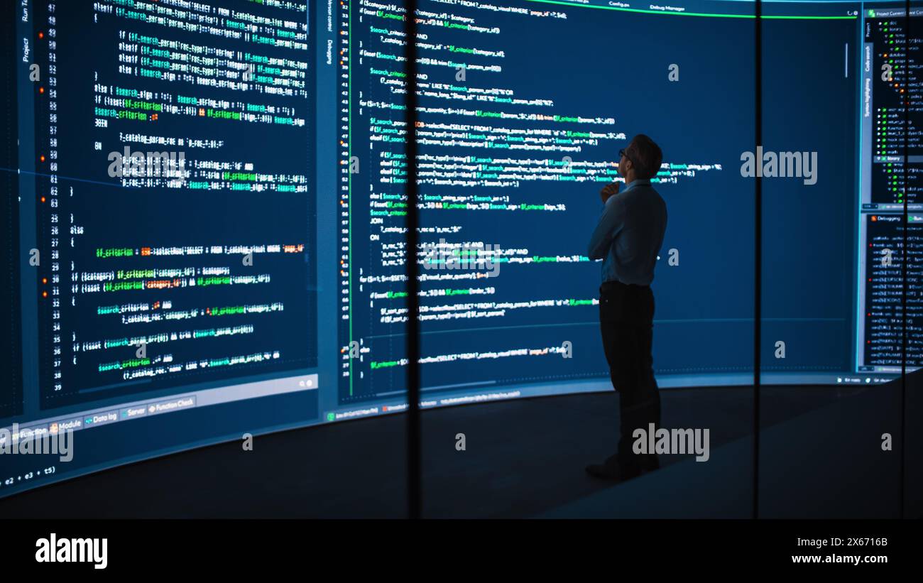 High-Tech Startup Concept: Innovative Male Software Engineer Standing, Doing Big Data Analysis on Wall Screen Showing Porgramming Code. Developing Futuristic e-Commerce App with Machine Learning. Stock Photo