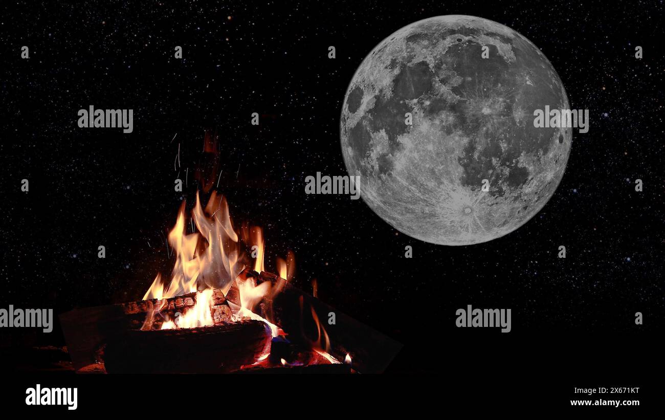 a bonfire burns at night against the background of mountains and sea with bright stars.. Stock Photo