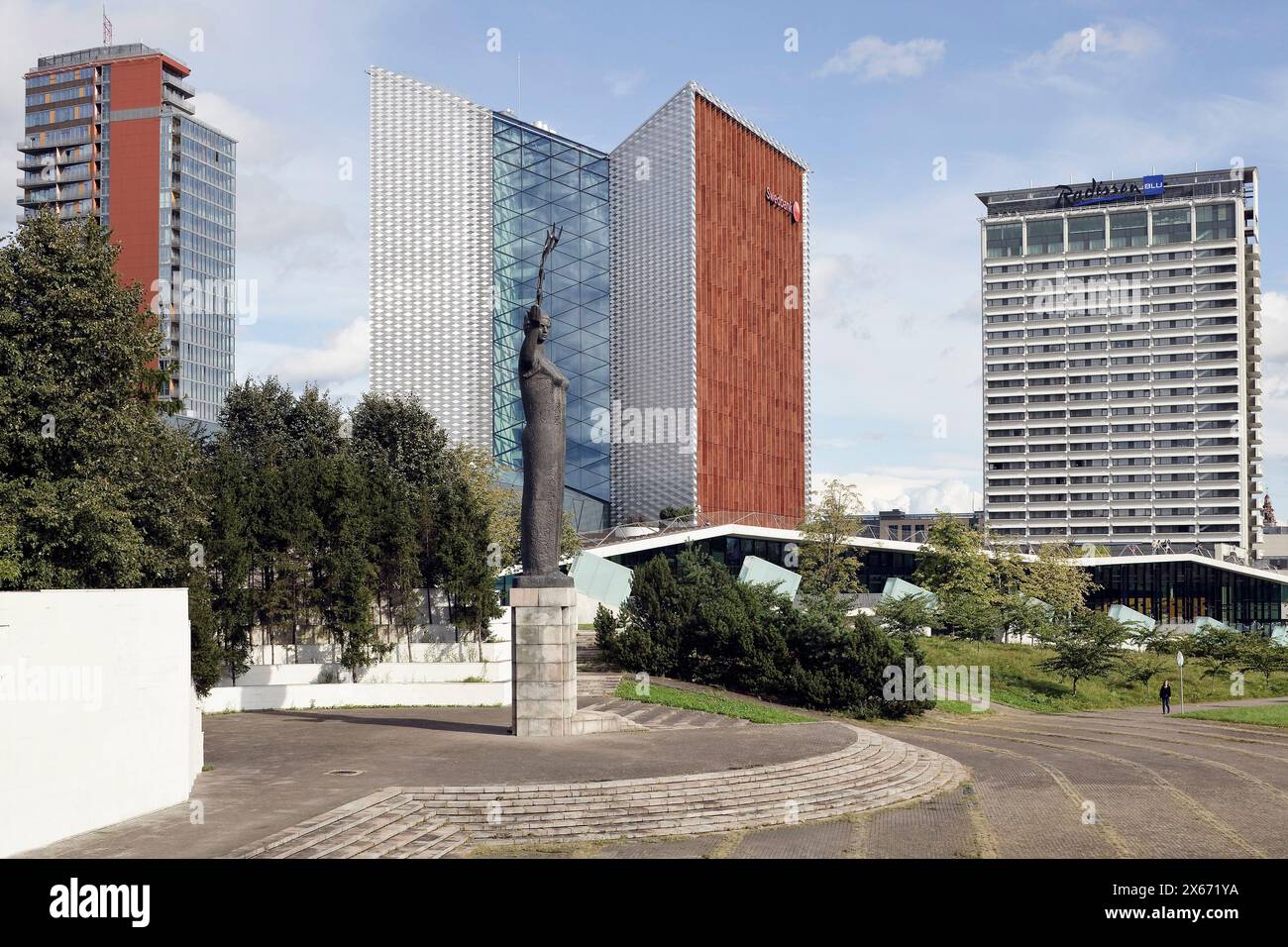 General view of area with several towers and statue in the foreground. SwedBank Vilnius, Lithuania, Vilnius, Lithuania. Architect: Audrius Ambrasas Ar Stock Photo