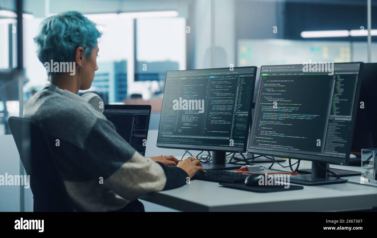 In Diverse Office: Female Programmer is Working on Desktop Computer, Screen Shows Coding Language User Interface. Digital Entrepreneur Creating Modern Software, e-Commerce App Design. Over Shoulder Stock Photo