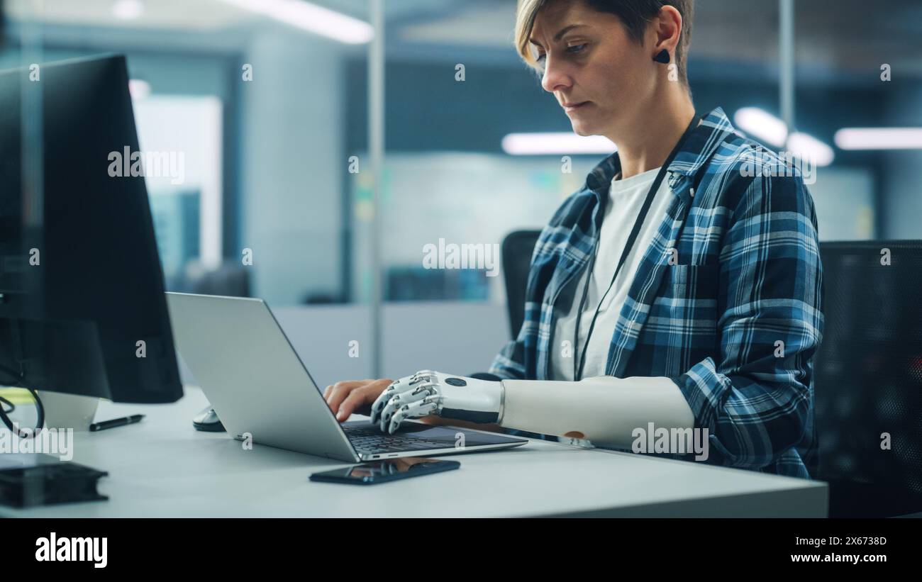 Diverse Body Positive Office: Portrait of Motivated Woman with Disability Using Prosthetic Arm to Work on Computer. Professional with Futuristic Thought Powered Myoelectric Bionic Hand Stock Photo