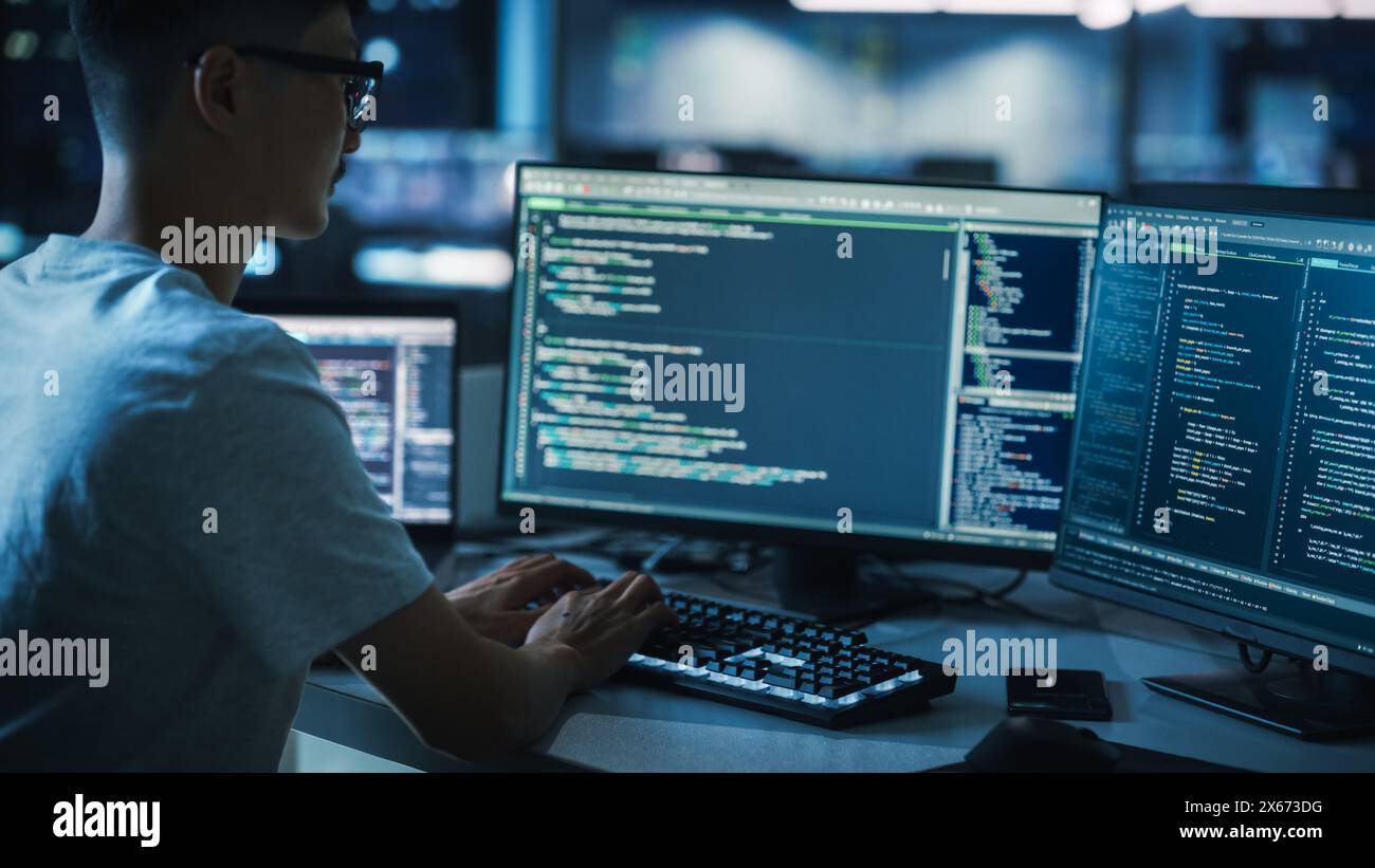 Night Office: Young Handsome Man in Working on Desktop Computer. Digital Entrepreneur Typing Code, Developing Modern Software, e-Commerce App Design, Developing of e-Business. Over Shoulder Stock Photo