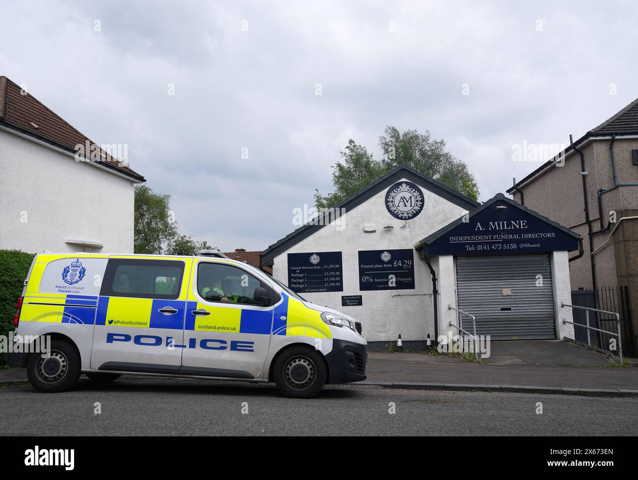 A police vehicle sits outside of A. Milne funeral directors in Balornock, Glasgow. An investigation is ongoing into to the conduct of a former funeral company that had branches in Glasgow and Dumbarton with regard to the storage/return of cremated remains and allegations of financial misconduct. Picture date: Monday May 13, 2024. Stock Photo