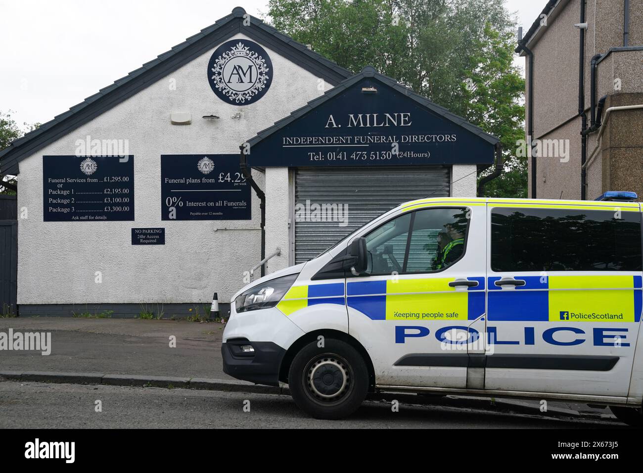 A police vehicle sits outside of A. Milne funeral directors in Balornock, Glasgow. An investigation is ongoing into to the conduct of a former funeral company that had branches in Glasgow and Dumbarton with regard to the storage/return of cremated remains and allegations of financial misconduct. Picture date: Monday May 13, 2024. Stock Photo