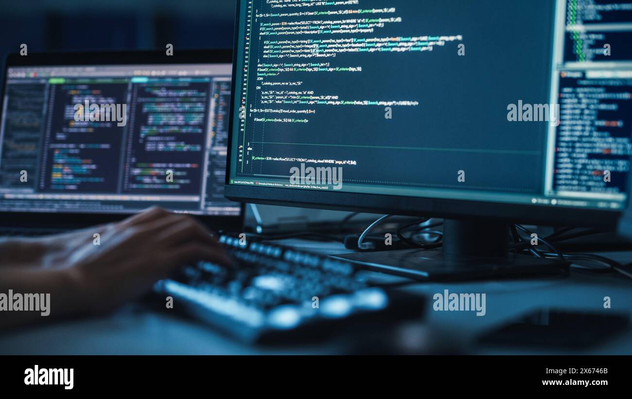 Close-up Focus on Person's Hands Typing on the Desktop Computer Illuminated Keyboard. Screens Show Coding Language User Interface. Software Engineer Create Innovative Commerce App. Program Development Stock Photo