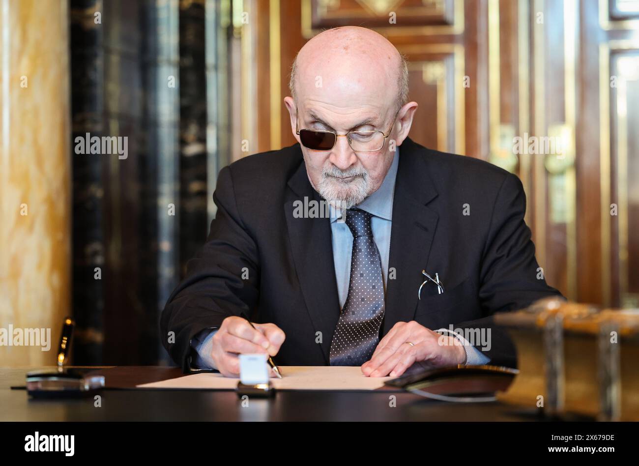 Hamburg, Germany. 13th May, 2024. The Indian-British writer Salman Rushdie signs the city's Golden Book in the town hall. Credit: Christian Charisius/dpa/Alamy Live News Stock Photo