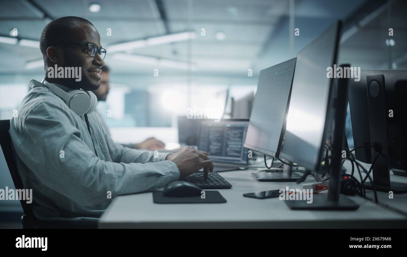 Authentic Office: Portrait of Black IT Programmer Working on Desktop Computer. Male Website, Software Engineer Developing App, Program, Video Game. Stylish Side View Shot Stock Photo