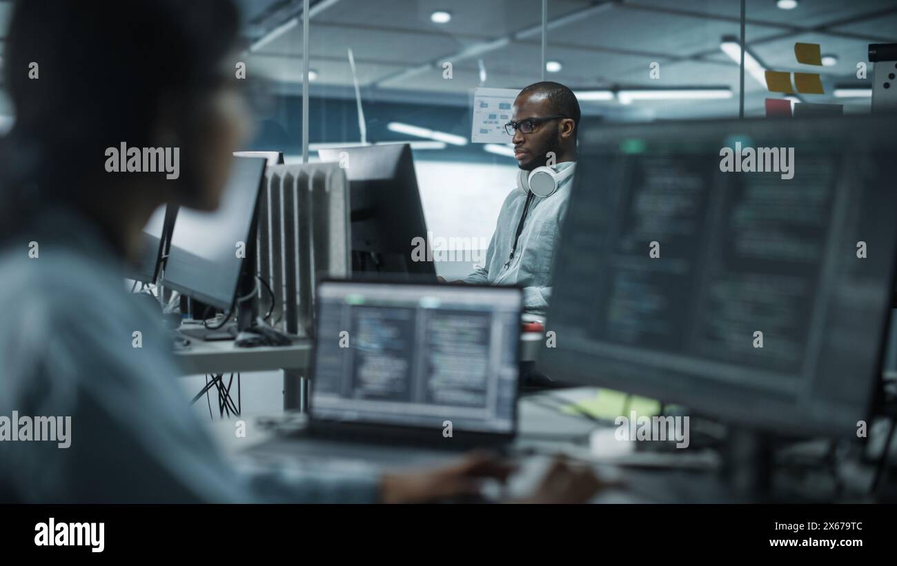 Diverse Multi-Ethnic Team in Office: Indian Female and Black Male IT Programmers Working on Desktop Computer. Specialists Creating Software. Engineers Developing App, Program. Stock Photo