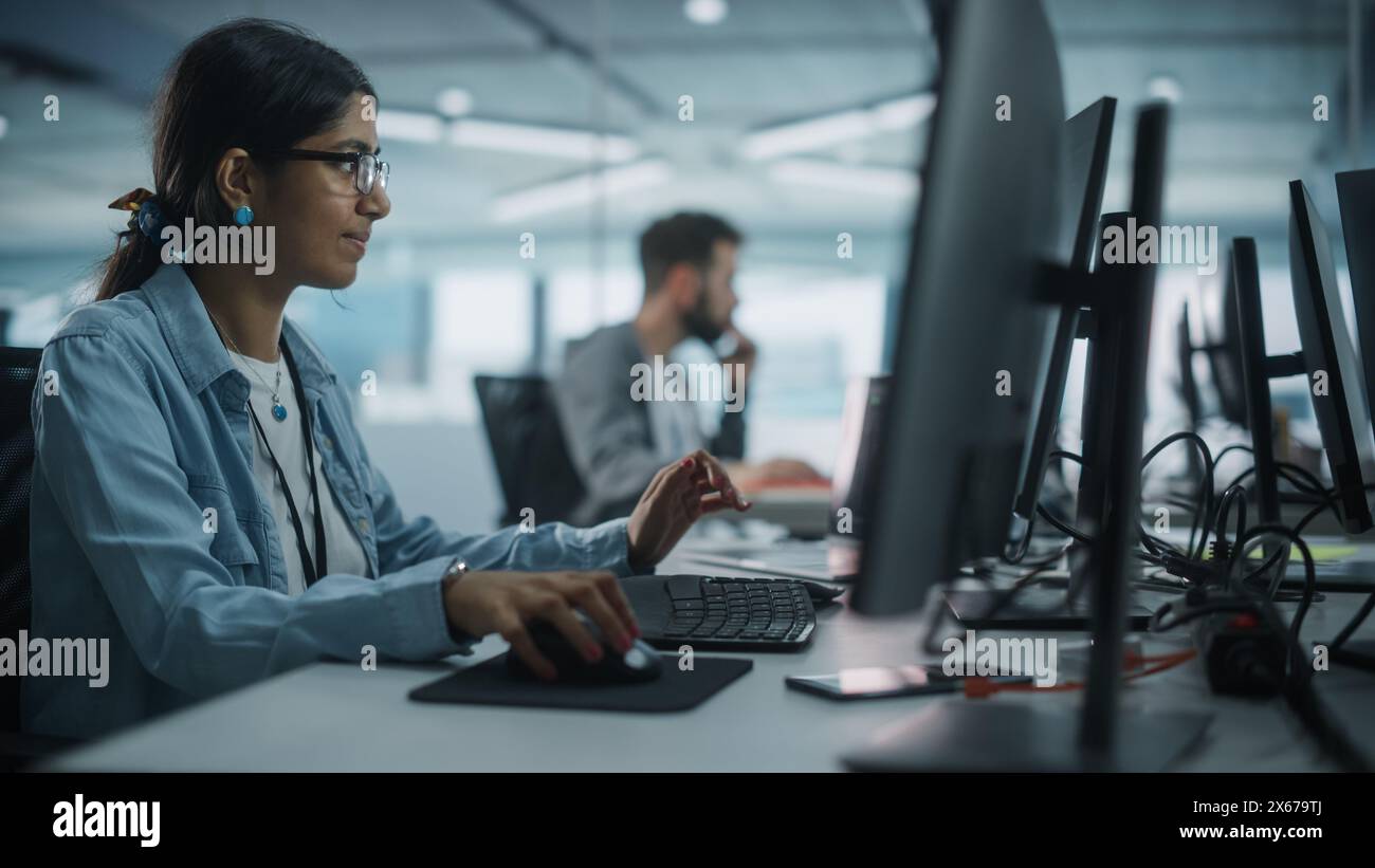 Real Diverse Office: Indian IT Programmer Working on Desktop Computer. Female Specialist Creating Innovative Software. Engineer Developing App, Program, Video Game. Writing Code in Terminal. Stock Photo