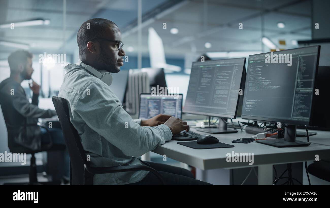 Authentic Office: Enthusiastic Black IT Programmer Starts Working on Desktop Computer. Male Website Developer, Software Engineer Developing App, Video Game. Terminal with Coding Programming Language Stock Photo