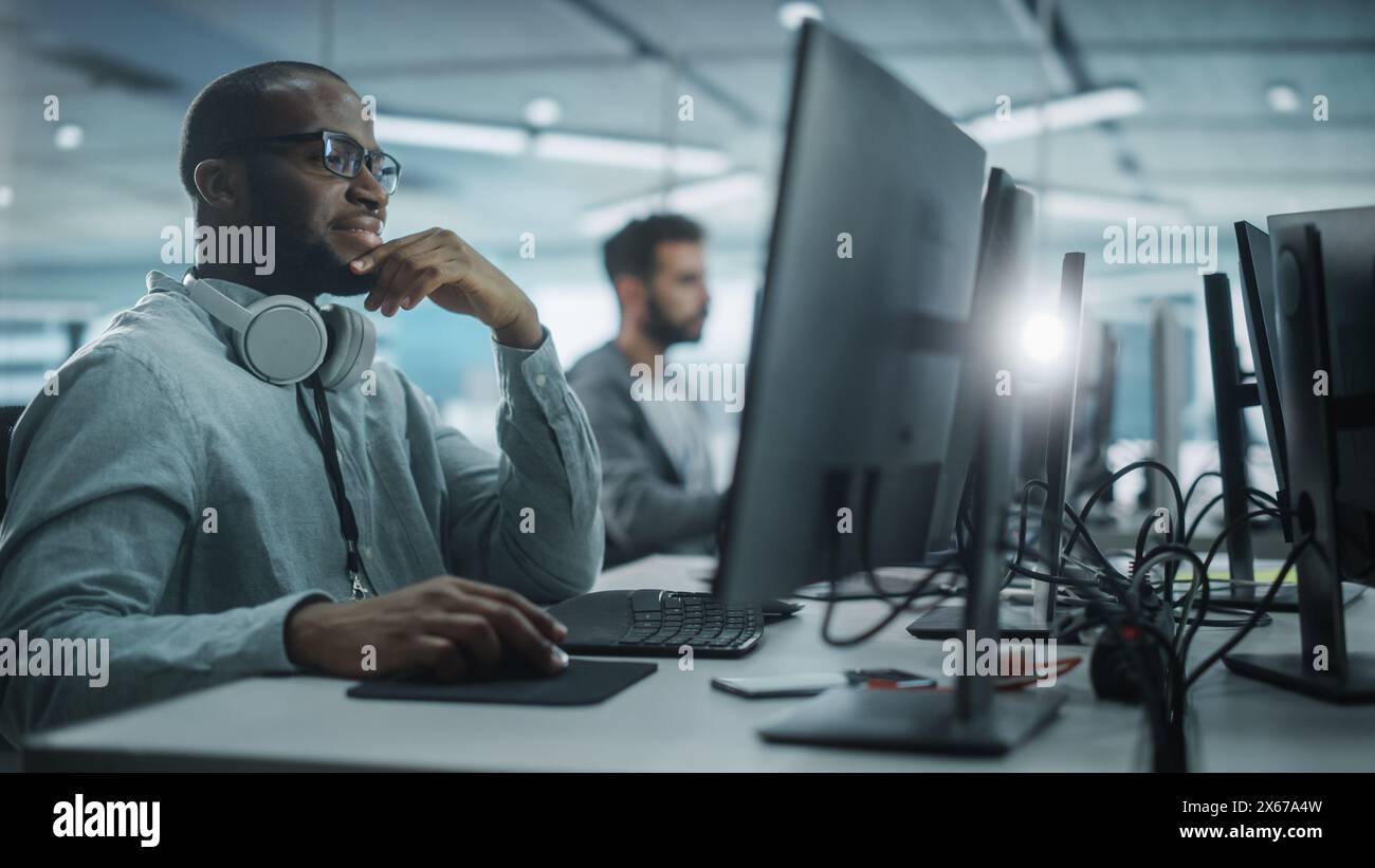 Authentic Office: Motivated Black IT Programmer Working on Desktop Computer. Male Website, Software Engineer Developing App, Program, Video Game. Terminal with Coding Language. Stock Photo