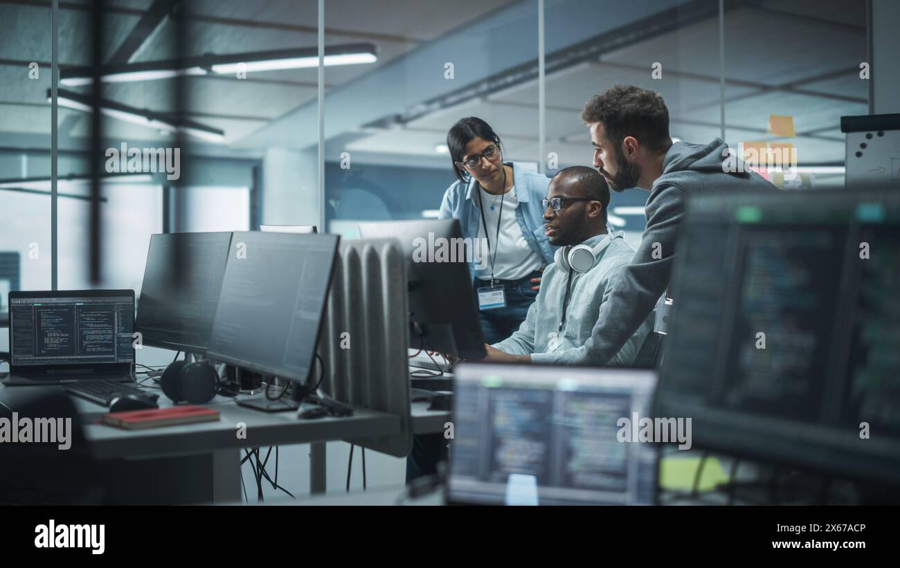 Diverse Multi-Ethnic Team Working in Modern Office: Group of IT Programmers Gather Around Desktop Computer, Talking, Finding Solution. Specialists Create Software. Engineers Develop App, Program Stock Photo