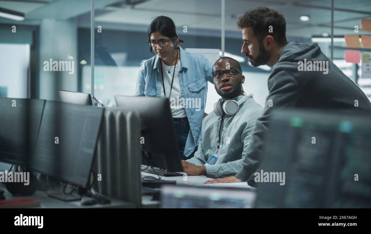Diverse Multi-Ethnic Team in Modern Office: Teamwork of IT Programmers Gather Around Desktop Computer, Talking, Finding Solution. Specialists Create Software. Engineers Develop App, Program Stock Photo