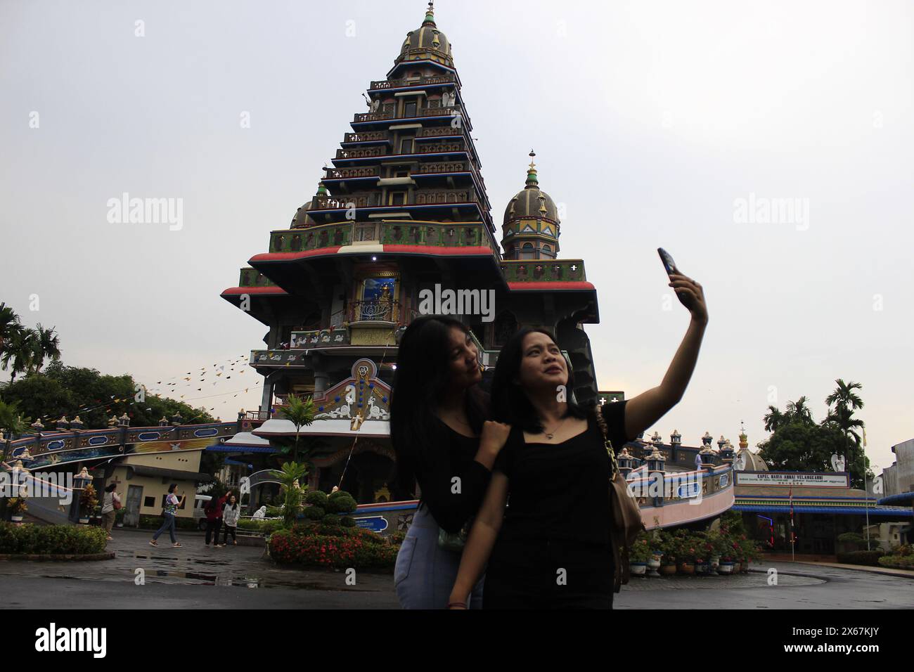 Medan Selayangh, North Sumatra, Indonesia. 11th May, 2024. Two visitors at the Annai Velangkani church, Indonesia, North Sumatra, take a selfie with the backdrop of a temple-like church building in India. (Credit Image: © Kartik Byma/ZUMA Press Wire) EDITORIAL USAGE ONLY! Not for Commercial USAGE! Stock Photo