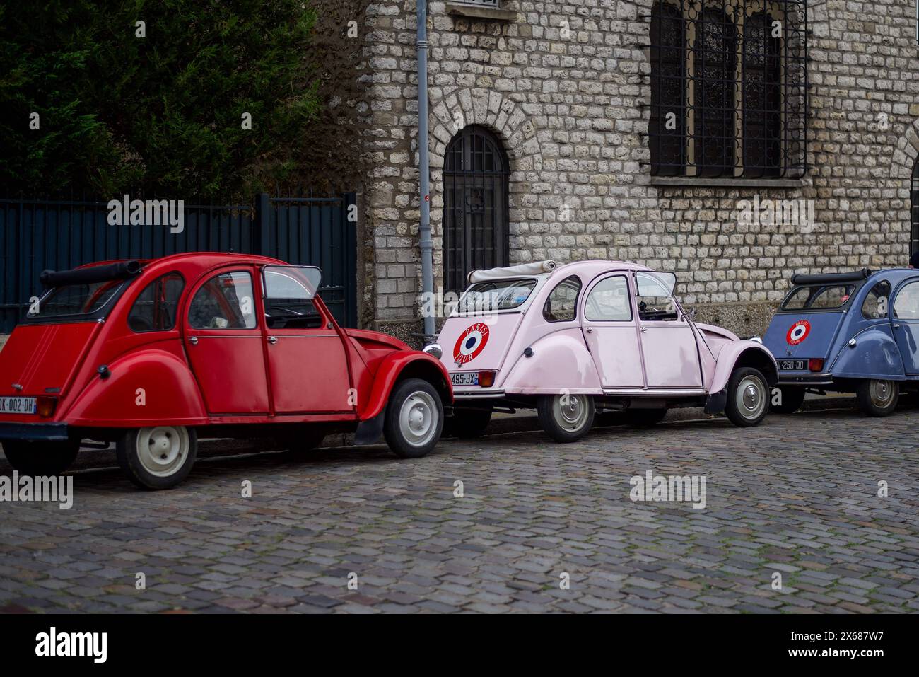 Paris, France, 09.17.2023 Red, pink and blue Citroën 2CV cars near Montmartre. These are cars used for guided tours around Paris. Stock Photo