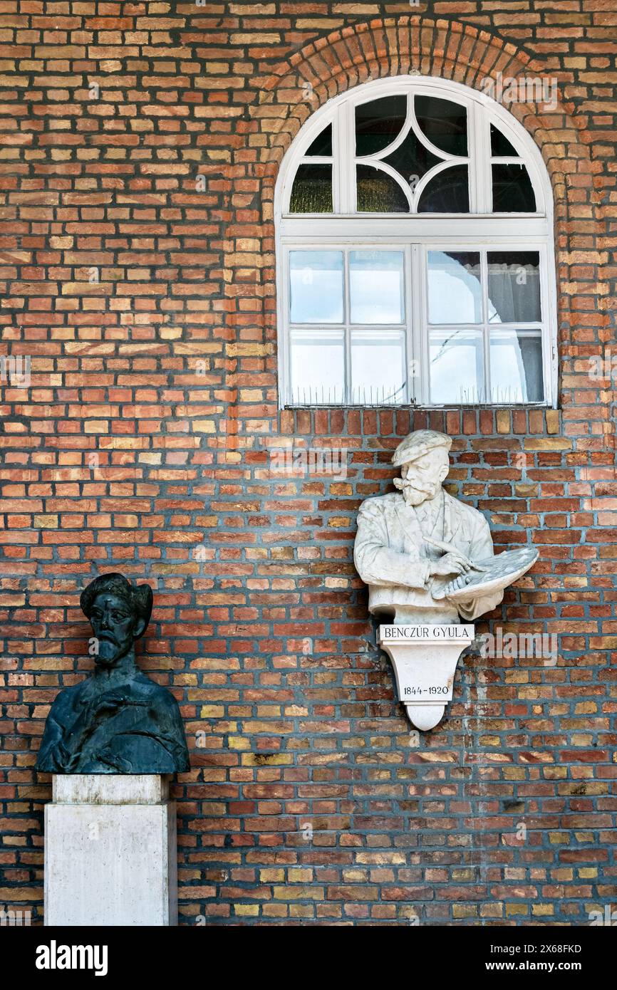 Sculptures on a brick wall in the gallery of the building of the Faculty of Medicine of the University of Szeged. Stock Photo
