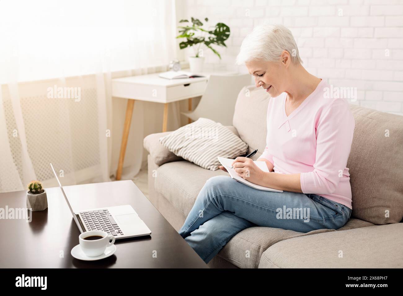 Senior Woman Sitting on Couch, Taking Notes Stock Photo