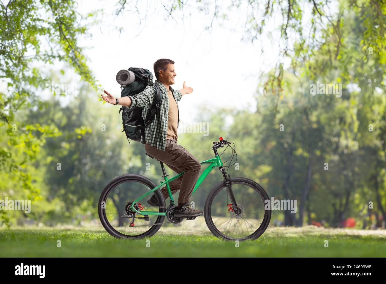 Backpacker riding a bicycle in a park Stock Photo