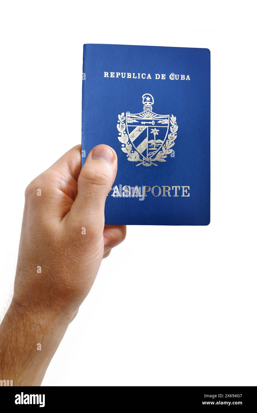 Close-up on a man's hand holding a Cuban passport against a white background. Stock Photo