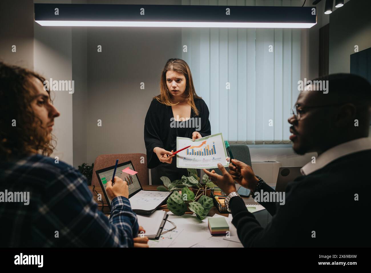 Multicultural team discussing growth statistics in modern office setting Stock Photo
