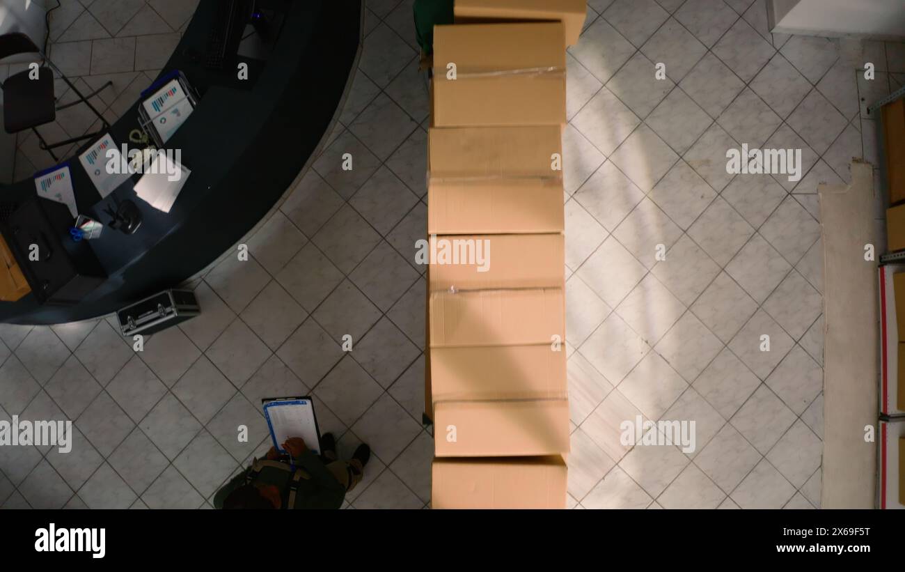 Top down view of warehouse chief supply chain officer examining cardboard box parcels in parallel, comparing findings. Depository staff members making sure stocks and inventory are well organized Stock Photo