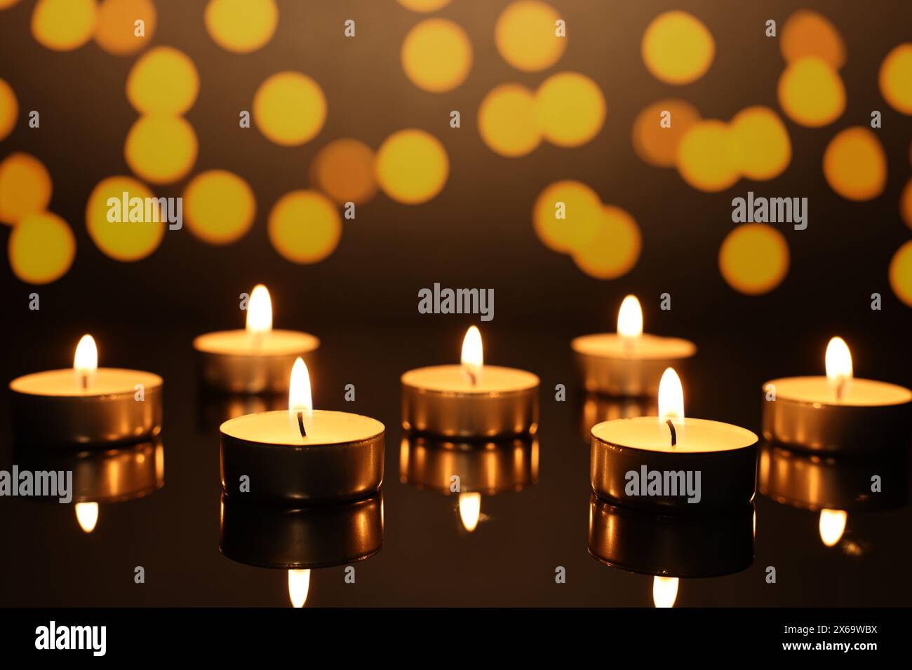 Burning candles on mirror surface in darkness, bokeh effect Stock Photo ...