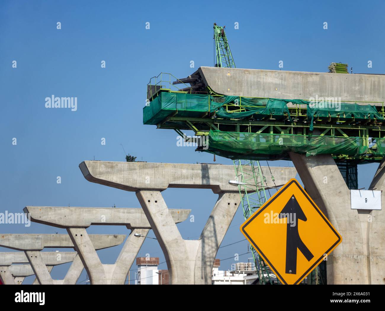 Pillars of an elevated highway under construction with a traffic sign below it Stock Photo
