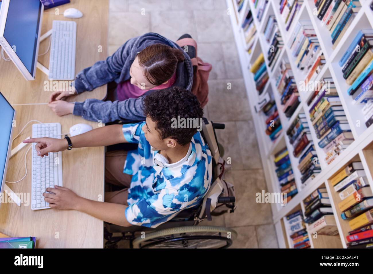 Top view at two teenagers using computer in school library and doing ...