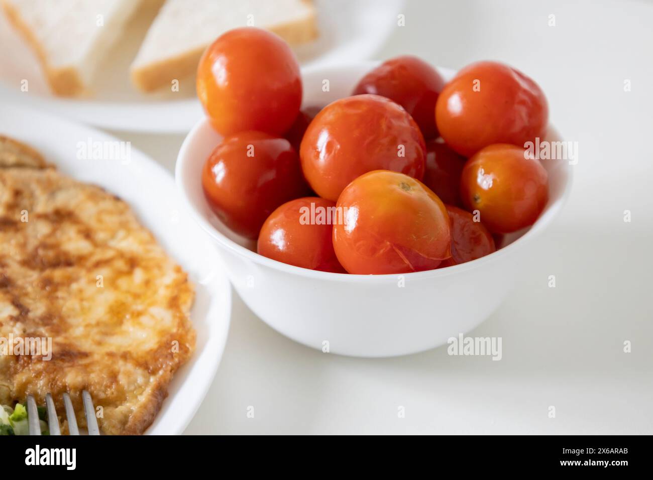 Red pickled tomatoes in a white plate close-up on a table Stock Photo