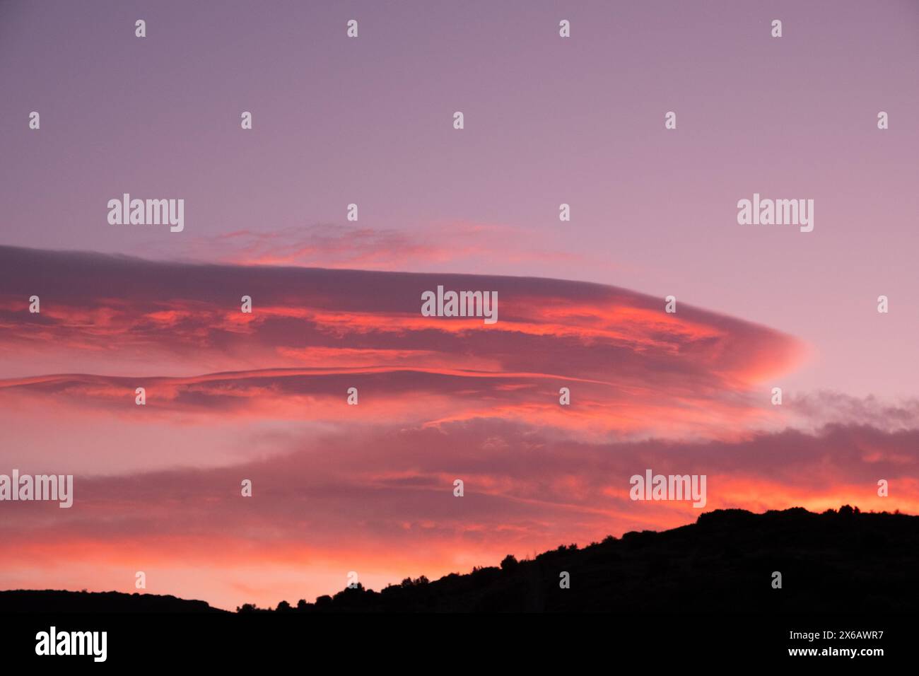 A dusk sky with scattered clouds displaying shades of orange and red Stock Photo
