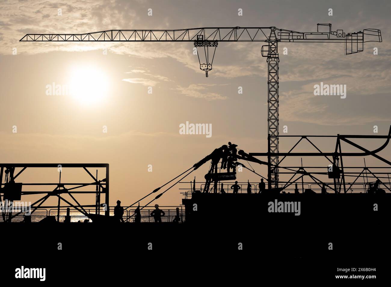 At the construction site was there are workers dismantling the tower crane and another tower crane standby for lifting with the sunset at sea. Stock Photo