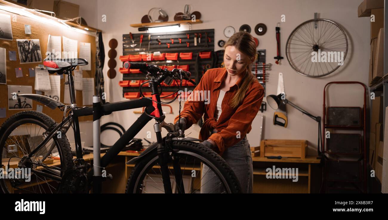 Young handywoman with bicycle during a repairman in home workshop or garage. DIY and hobby concept Stock Photo